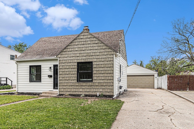 view of front of home with a shingled roof, a detached garage, an outbuilding, and a chimney