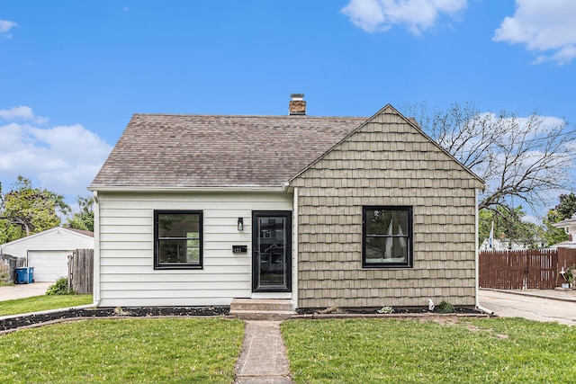 view of front of property featuring a shingled roof, a chimney, a detached garage, and an outdoor structure