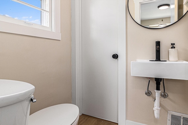 half bath featuring toilet and wood finished floors