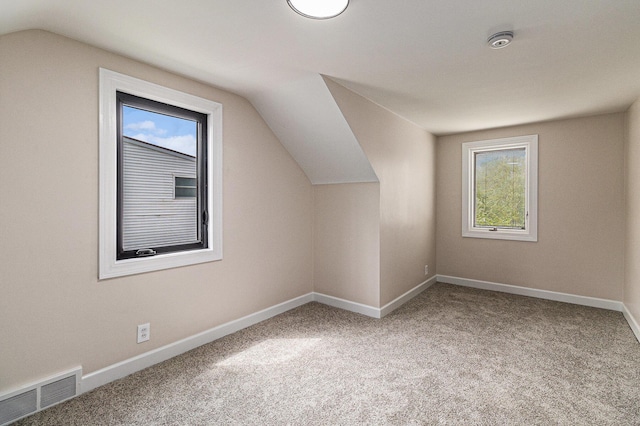 bonus room featuring lofted ceiling, plenty of natural light, baseboards, and carpet