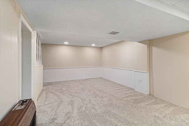finished below grade area featuring carpet, wainscoting, and a textured ceiling