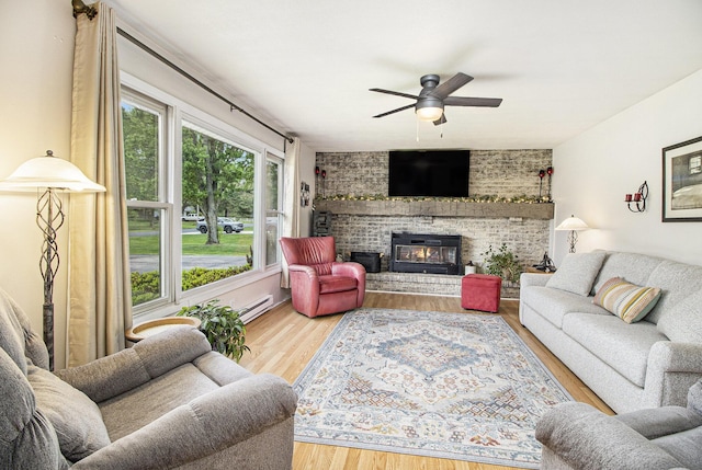 living area featuring ceiling fan, wood finished floors, a baseboard heating unit, and a fireplace