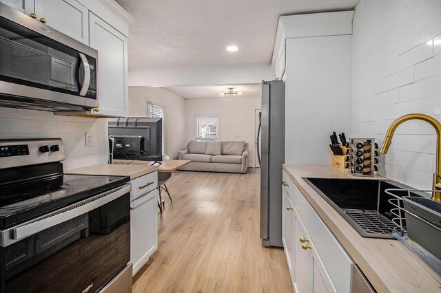 2228 Regent St, Kalamazoo, MI 49004 - kitchen with stainless steel appliances, a sink, light countertops, white cabinets, and recessed lighting