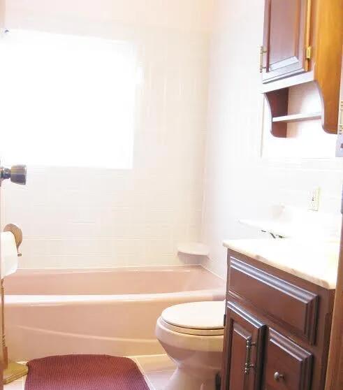 full bath with toilet, vanity, and  shower combination