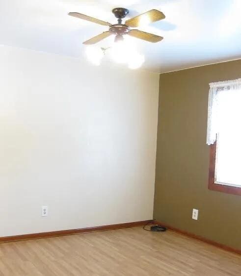 spare room with light wood-style floors, a ceiling fan, and baseboards