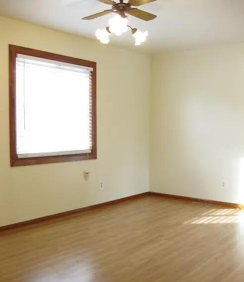 spare room featuring light wood-style flooring, baseboards, and a ceiling fan