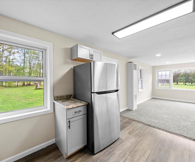 24108 Martinsville Rd, Belleville, MI 48111 - kitchen featuring freestanding refrigerator, baseboards, light wood-type flooring, open floor plan, and light stone countertops