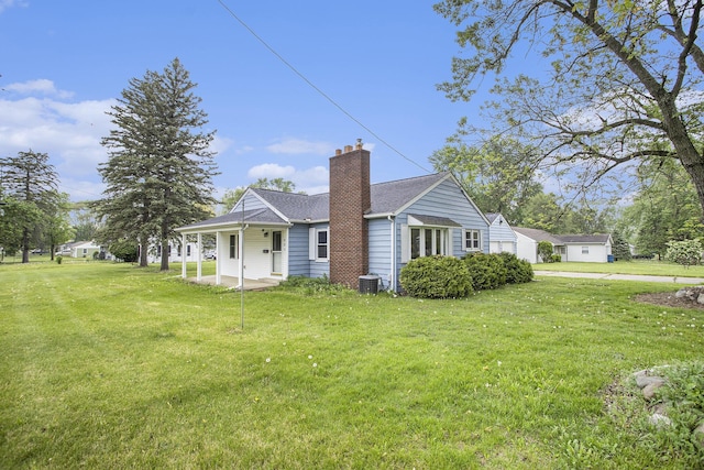 view of front of home with a chimney, a front lawn, and central AC