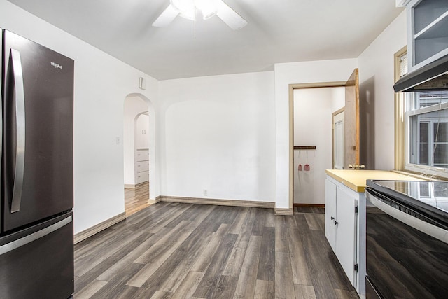 kitchen featuring freestanding refrigerator, range with electric cooktop, arched walkways, dark wood-style floors, and a ceiling fan