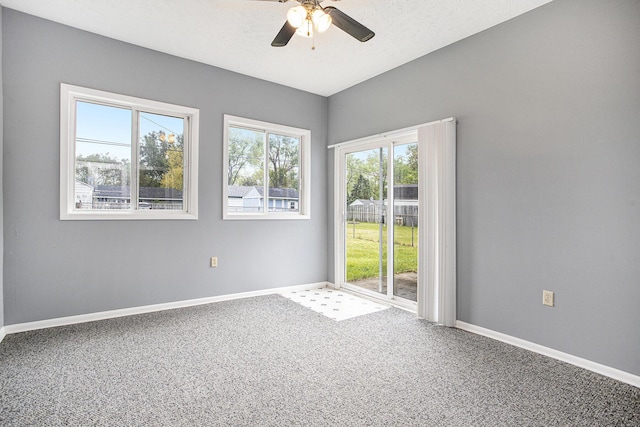 carpeted spare room featuring ceiling fan and baseboards