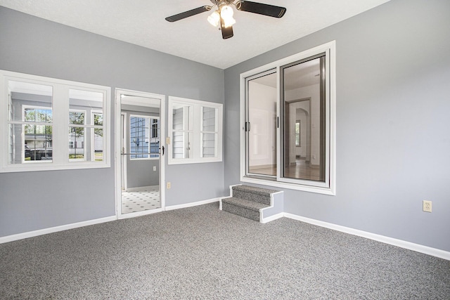 carpeted empty room with a ceiling fan and baseboards