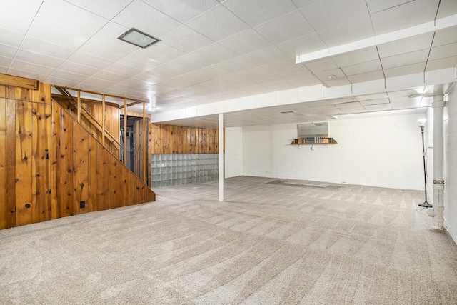 finished basement featuring carpet floors, wood walls, and stairway