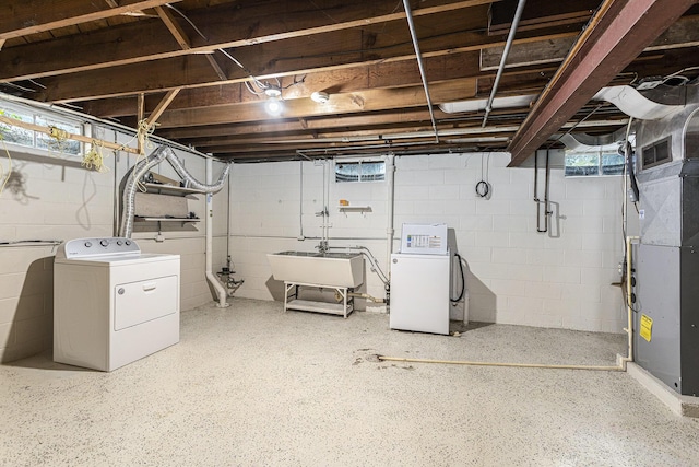 basement featuring washer and clothes dryer, a sink, heating unit, and healthy amount of natural light