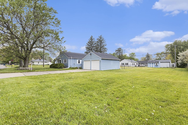 view of front of home featuring an outbuilding, concrete driveway, a front yard, and a detached garage