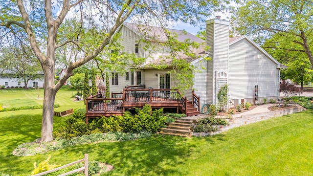 rear view of property with a deck, a chimney, and a lawn