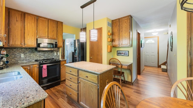 kitchen featuring stainless steel appliances, wood finished floors, tasteful backsplash, and brown cabinets