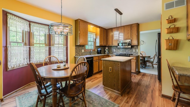 kitchen with appliances with stainless steel finishes, a kitchen island, a sink, and brown cabinetry