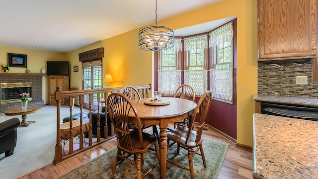 dining area featuring a chandelier, a fireplace, light wood-style flooring, and baseboards