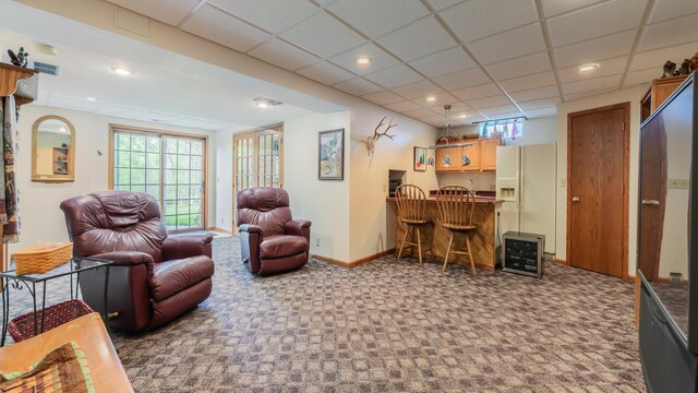 living room featuring a bar, carpet floors, healthy amount of natural light, baseboards, and a paneled ceiling