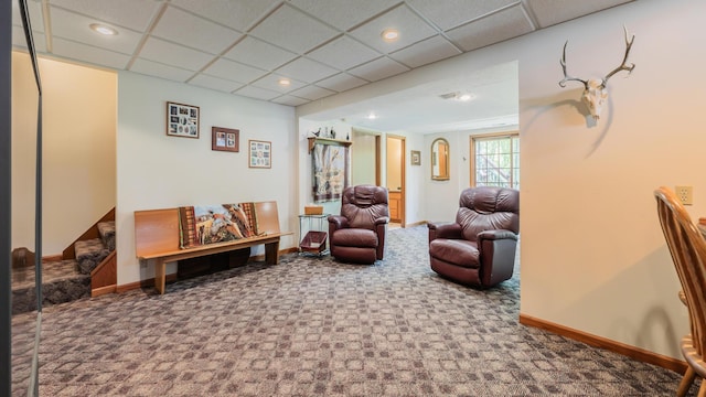 living area with carpet flooring, baseboards, and a paneled ceiling