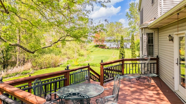 wooden terrace with outdoor dining space and a lawn