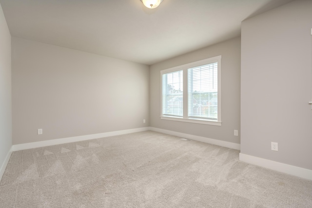 spare room with light colored carpet and baseboards