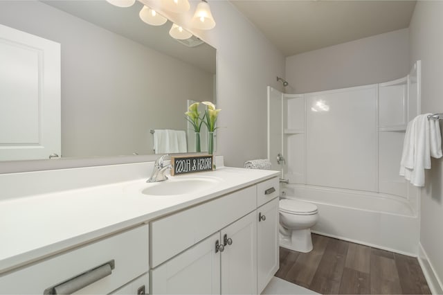 bathroom featuring wood finished floors, toilet, vanity, and shower / washtub combination