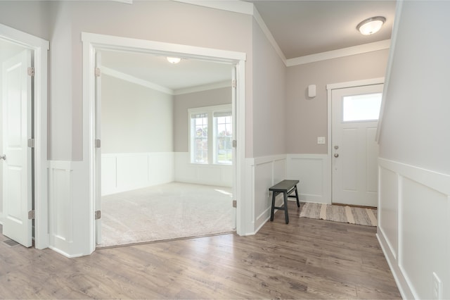 foyer entrance with ornamental molding, wainscoting, wood finished floors, and a decorative wall
