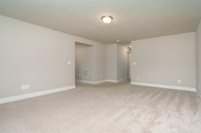 unfurnished room with light colored carpet and baseboards