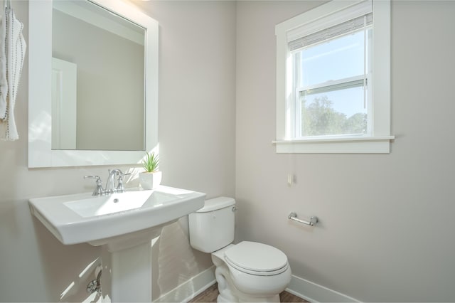half bathroom featuring baseboards and toilet
