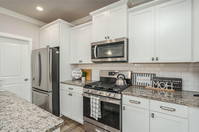 kitchen with appliances with stainless steel finishes, white cabinetry, light stone counters, and recessed lighting
