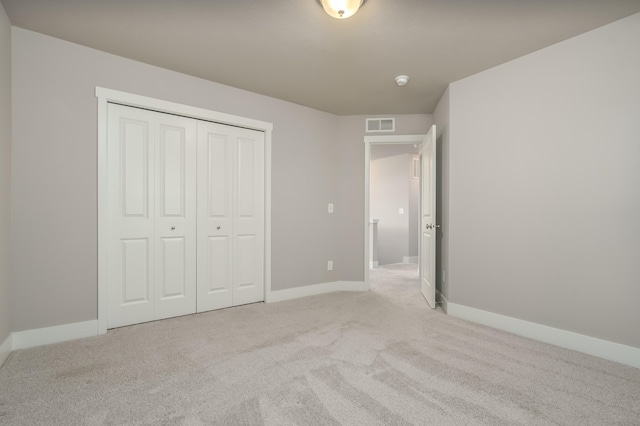 unfurnished bedroom with light colored carpet, baseboards, and a closet
