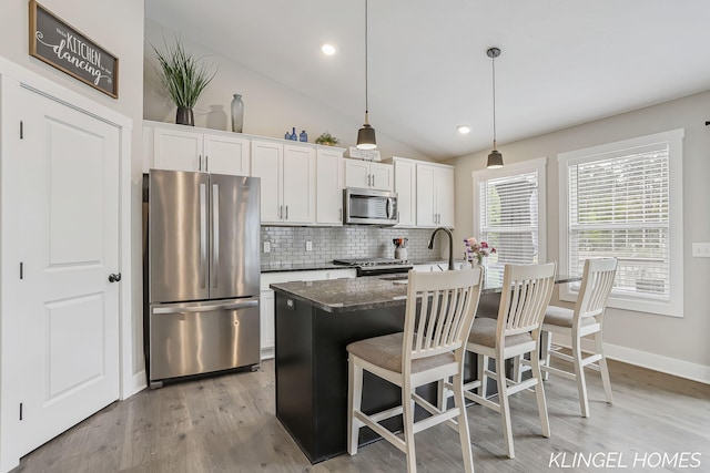 12745 Riverton Rd, Grand Haven, MI 49417 - kitchen with appliances with stainless steel finishes, tasteful backsplash, vaulted ceiling, a breakfast bar, and light wood-style flooring