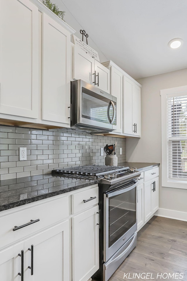 12745 Riverton Rd, Grand Haven, MI 49417 - kitchen featuring stainless steel appliances, backsplash, white cabinetry, and light wood finished floors