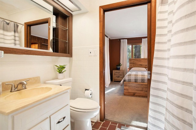 bathroom featuring ornamental molding, tile walls, vanity, toilet, and brick patterned flooring