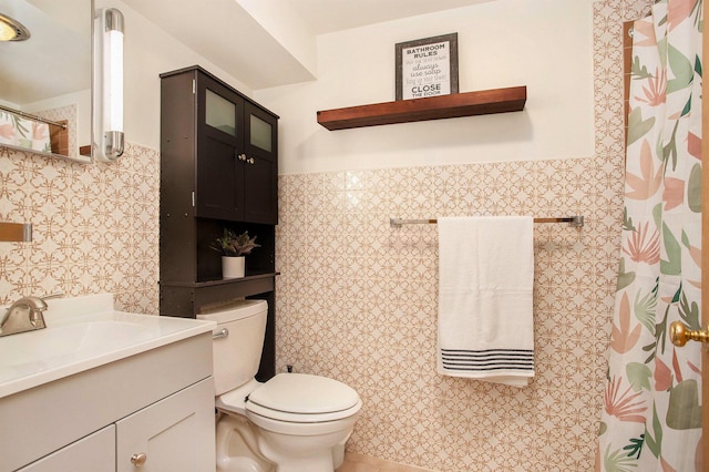 bathroom featuring tile walls, vanity, toilet, and a wainscoted wall
