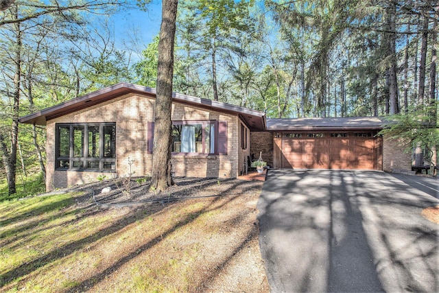 view of front of property featuring brick siding, driveway, and a garage
