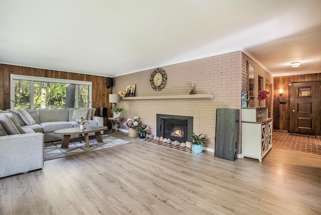 living area with wood walls, wood finished floors, crown molding, and a brick fireplace