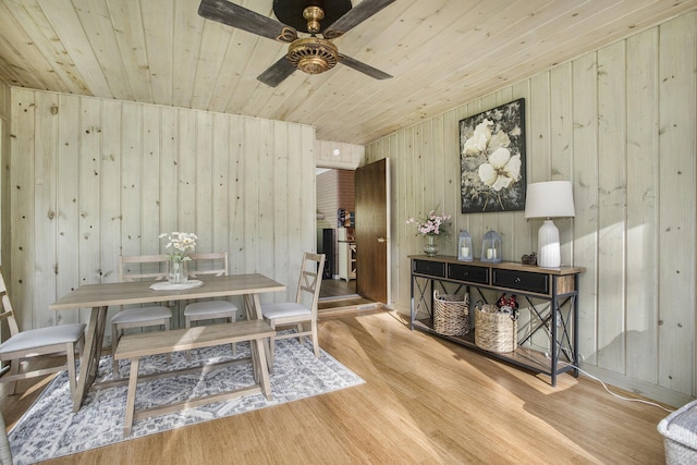 dining area featuring wooden ceiling, wood walls, wood finished floors, and ceiling fan