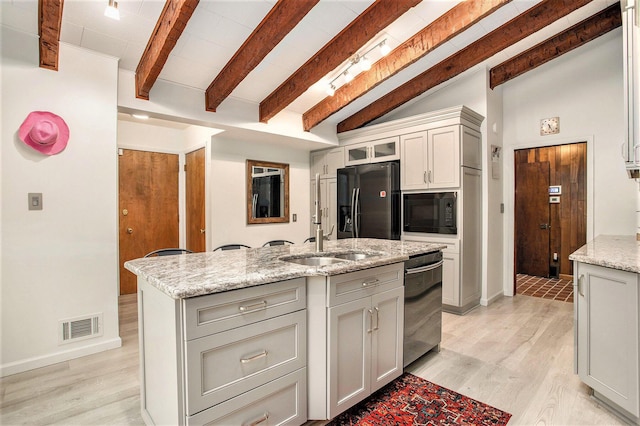 kitchen featuring black appliances, a sink, an island with sink, baseboards, and light stone countertops