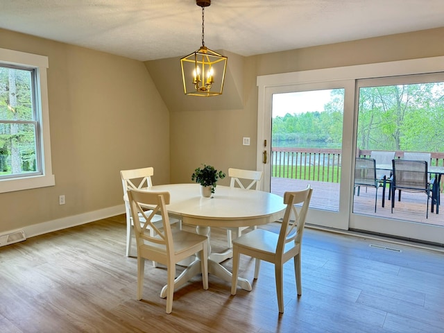 928 Lincoln St, Grand Rapids, MI 49534 - dining area with a chandelier, wood finished floors, baseboards, and vaulted ceiling