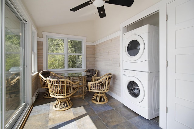2177 S Lakeshore Dr, Ludington, MI 49431 - laundry room with stacked washer and clothes dryer, wood walls, a ceiling fan, and stone finish flooring
