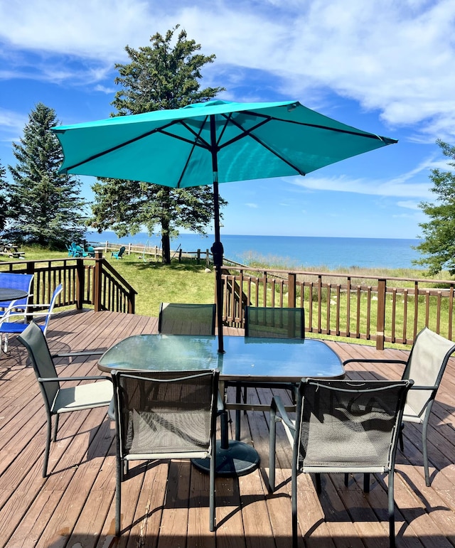 2177 S Lakeshore Dr, Ludington, MI 49431 - wooden deck featuring outdoor dining area, a water view, and a lawn