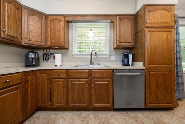 kitchen featuring dishwasher, a sink, brown cabinets, and light countertops