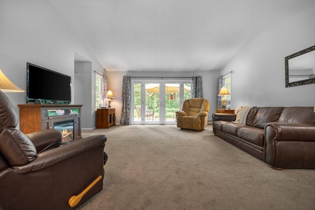 carpeted living room featuring lofted ceiling, plenty of natural light, and a glass covered fireplace