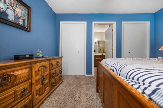 bedroom featuring light colored carpet and ensuite bathroom