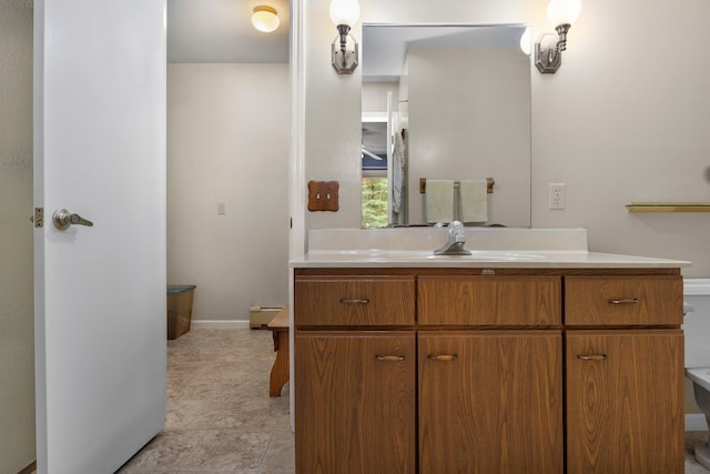 bathroom with vanity, toilet, and baseboards
