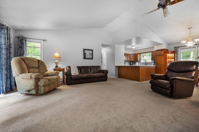 carpeted living area with vaulted ceiling, plenty of natural light, a ceiling fan, and a chandelier