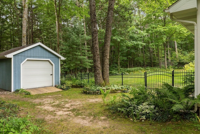 view of yard with fence, a storage unit, an outbuilding, and a forest view