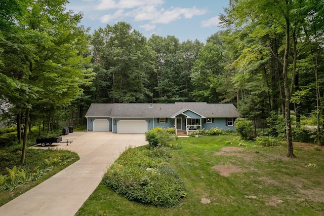 view of front facade featuring an attached garage, driveway, a view of trees, a front lawn, and covered porch